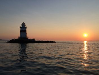 Lighthouse set in a new england sound, brilliant sunset in the distance. 