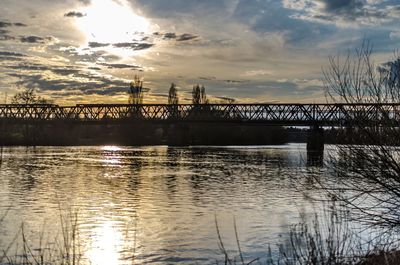 Bridge over river against sky during sunset