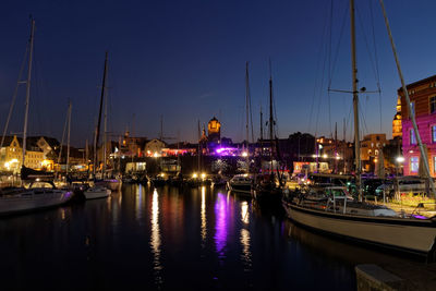 Boats moored at harbor in city at night