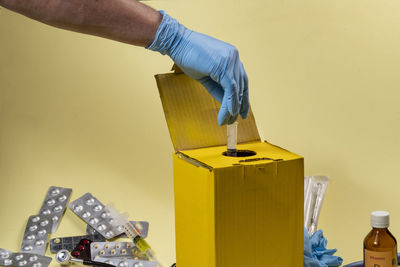 Yellow disposal box for contaminated or infectious products in a hospital. hand putting a syringe