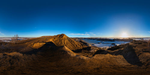 Panoramic view of rocks on land against clear blue sky