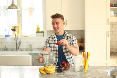 Portrait of smiling young man having food at home