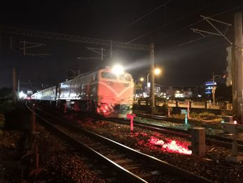 Railroad tracks against sky at night