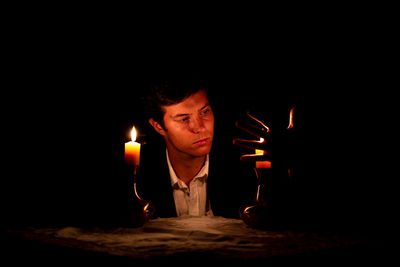 Portrait of man with burning candle in darkroom
