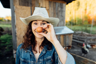 Funny woman farmer in denim with a fresh egg, making a funny face