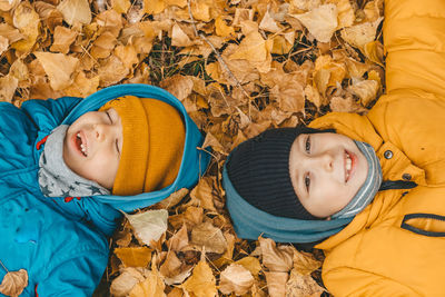 Children lie on yellow leaves on the ground. boys in jacket, scatters leaves in an autumn park. 