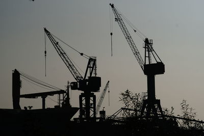 Low angle view of cranes at construction site against sky