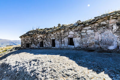 Built structure by rocks against clear blue sky