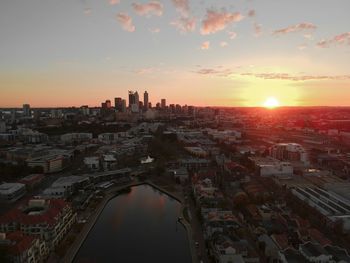 Aerial view of city buildings against sky during sunset