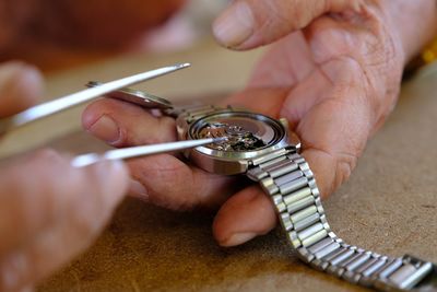 Cropped image of person repairing wristwatch on table