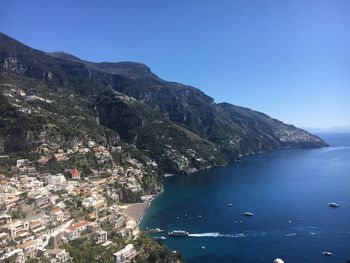 Scenic view of sea and mountains against clear blue sky