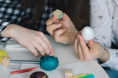 Close-up of siblings drawing on easter eggs at table