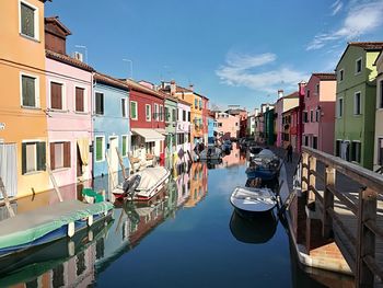 Boats moored in canal amidst buildings against sky