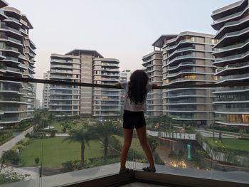 Full length of girl standing against modern buildings in city