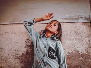 Portrait of young woman standing against wall