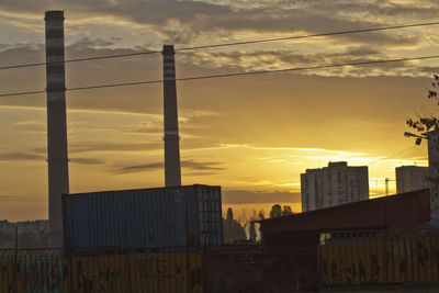 Silhouette bridge and buildings against sky during sunset