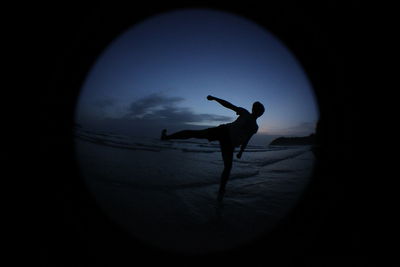 Silhouette man at beach against sky at night