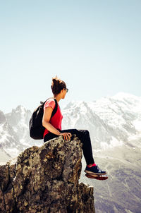 Man on rock by mountain against sky