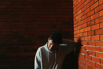 Young man standing against brick wall