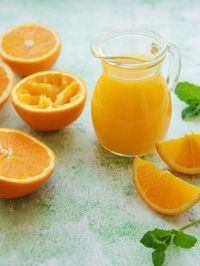 Glass jug of fresh orange juice with fresh fruits