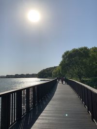 People on bridge over sea against sky