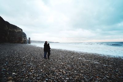 People standing on beach against sky