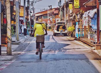 Rear view of man riding bicycle on street in city
