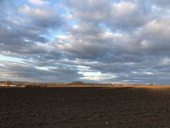 Scenic view of field against cloudy sky