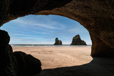 Scenic view of beach against sky seen through cave