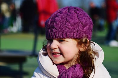 Close-up of smiling girl wearing purple knit hat outdoors