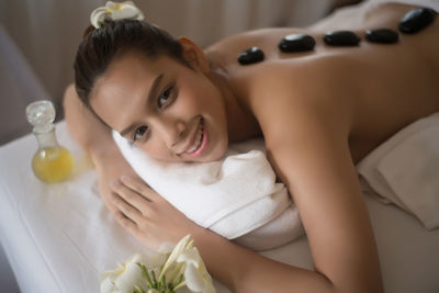 Portrait of smiling young woman lying on massage table in spa