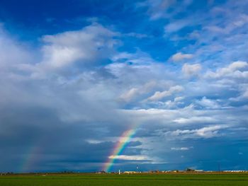 Rainbow over field against blue sky