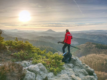 Tourist hold travel tripod. photographer climbed on peak for photographing the sunrise on hill top