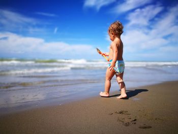 Toddler girl walking on sand against sea at beach