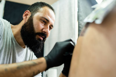 Close-up of artist tattooing customer in studio