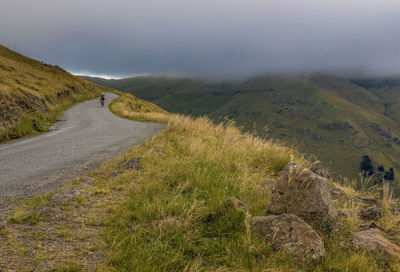 View of sumner road in cloudy stormy day, man riding bicycle visible on the road, christchurch