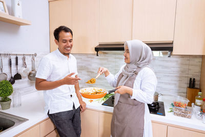 Friends standing on cutting board at home