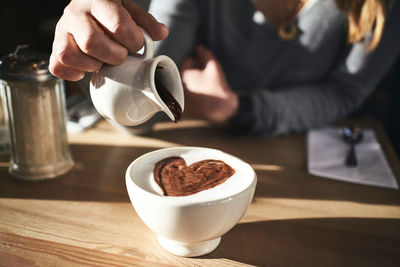 Midsection of man holding coffee cup on table