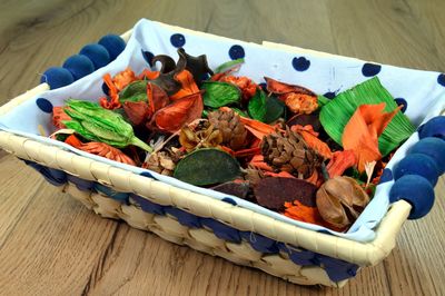 Dried flowers and pine cones in wicker basket on wooden table