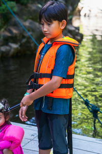  young boy wearing life jacket is feeding fish at the kelah sanctuary in lubuk kejor.