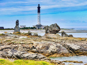 Lighthouse by sea against sky