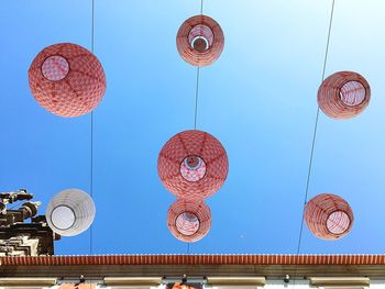 Low angle view of lanterns against clear blue sky