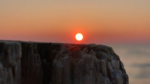 Scenic view of rock formation against orange sky