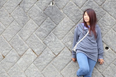 Portrait of woman with long hair standing against wall