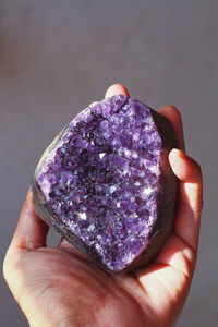 Cropped hand holding crystal against gray background