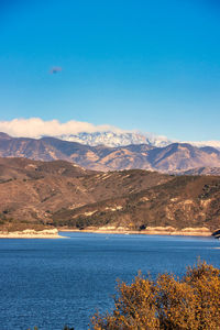 Scenic view of lake and mountains against blue sky