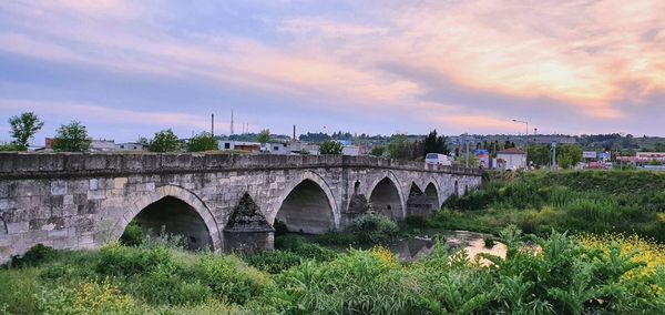Arch bridge over river against sky during sunset