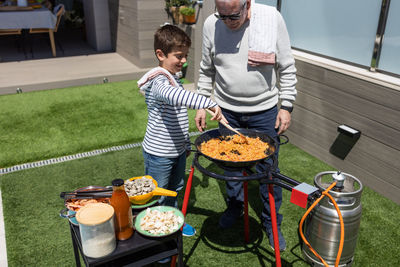 Grandfather and grandson preparing a paella in the garden