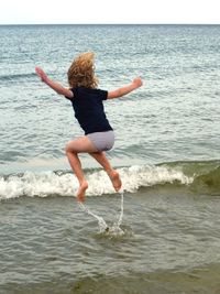 Rear view of girl jumping at beach