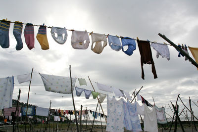 Low angle view of laundry drying on clotheslines at beach